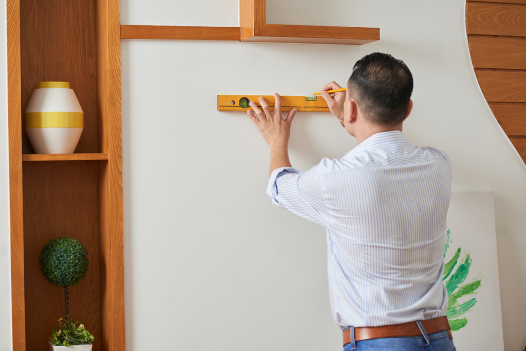 Homem medindo as paredes para decorar o seu apartamento.